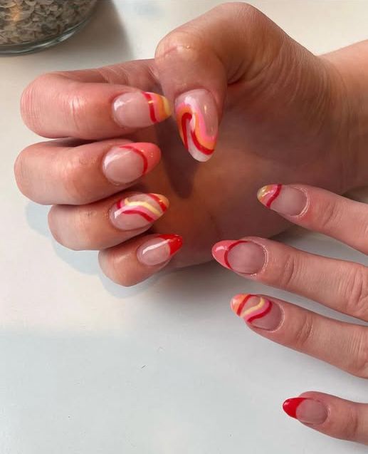A close up of a person 's nails with a red and yellow design.