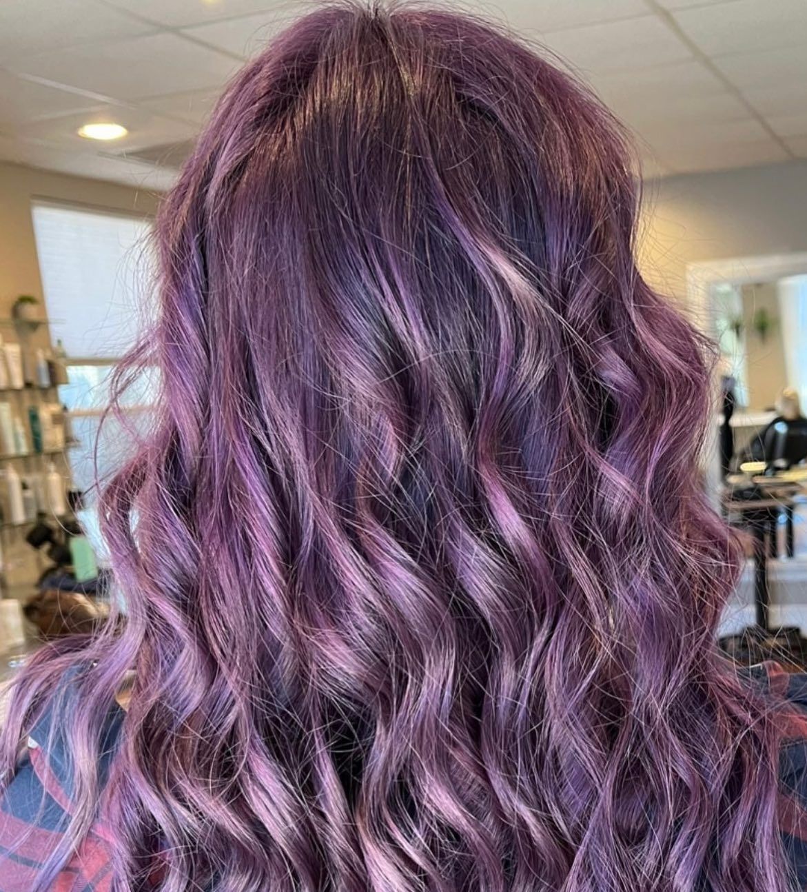 A woman with purple hair is standing in a salon.