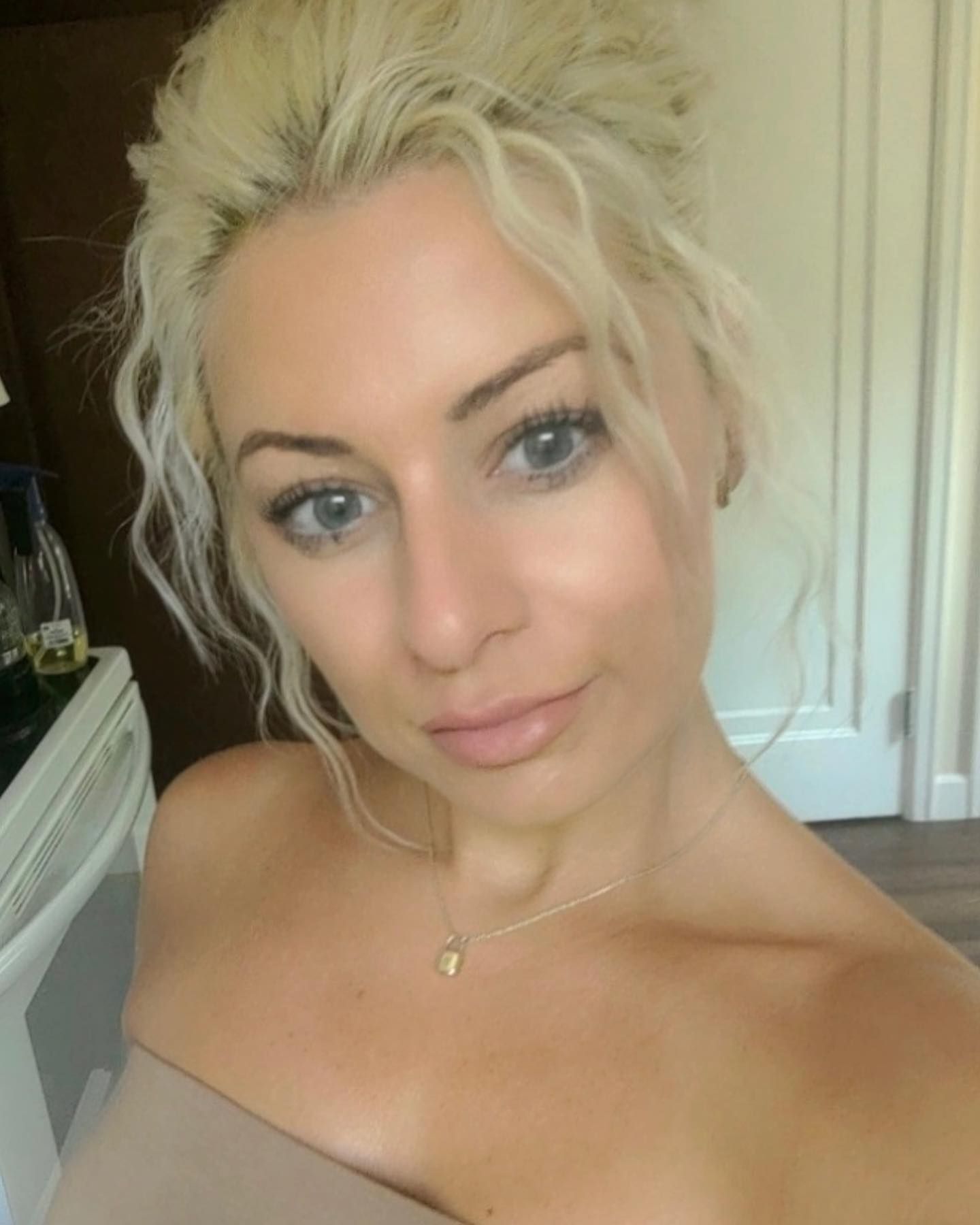 A woman is taking a selfie with her hair in a bun.