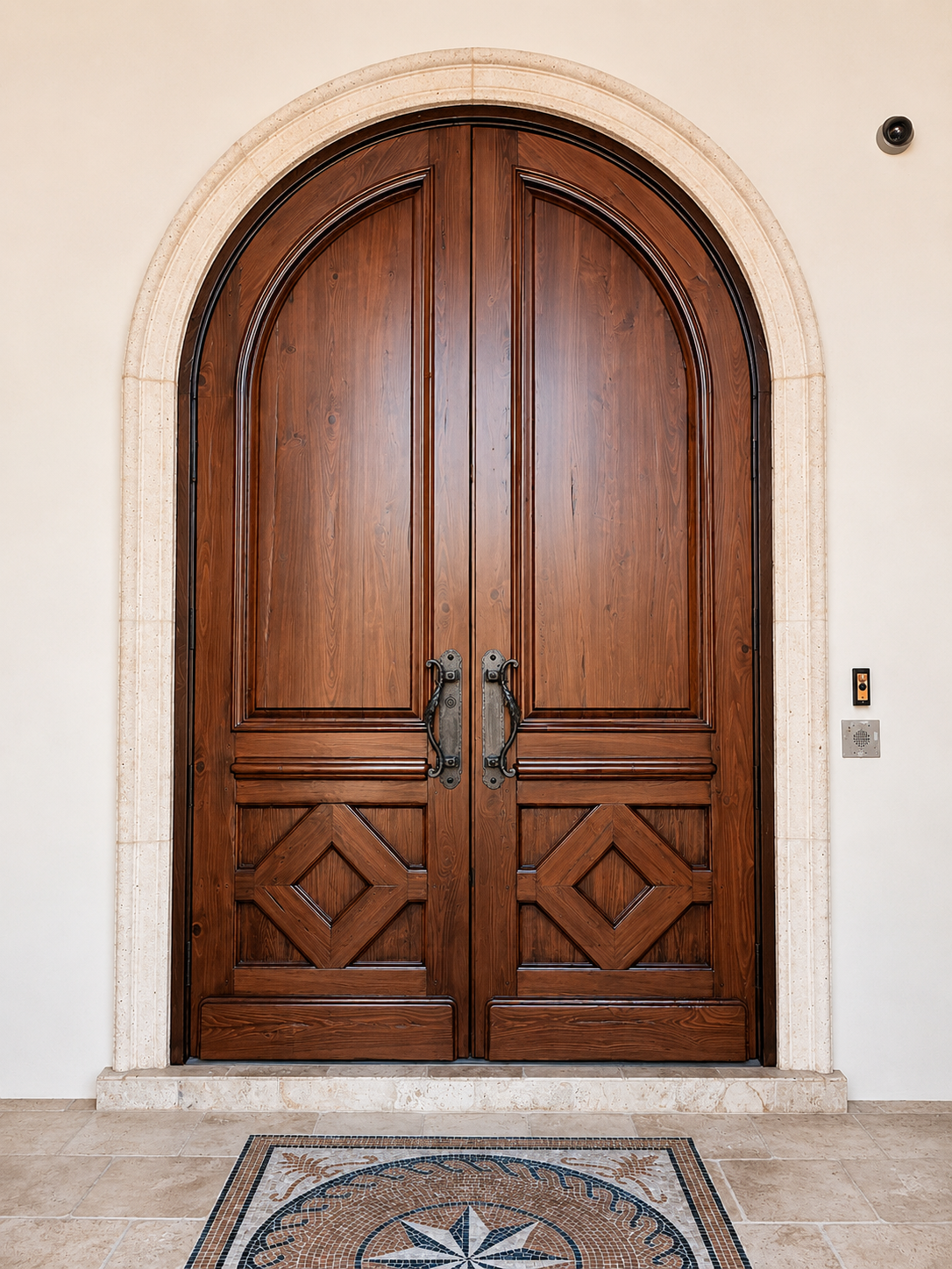 Arched wooden double doors with ornate iron handles in a stone doorway over a tiled floor.