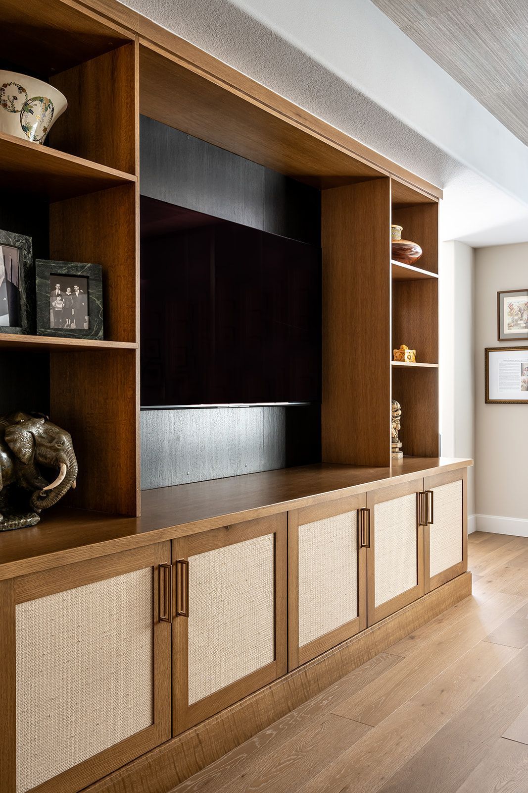 Built-in wood TV cabinet with woven cabinet doors in a bright modern living room