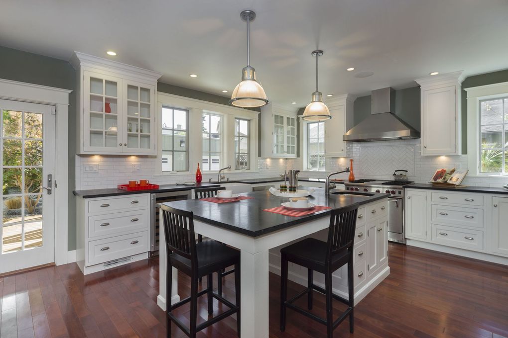 Bright kitchen with white cabinets, dark island, and pendant lights.