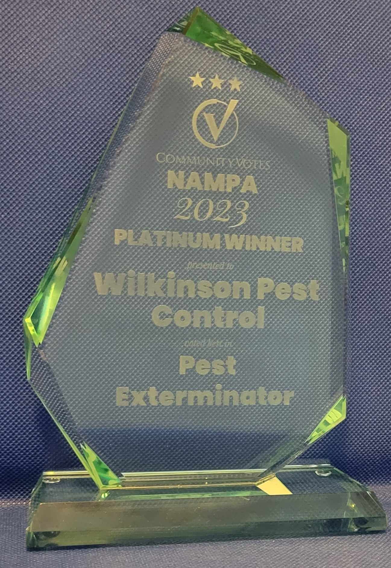 A trophy for wilkinson pest control is sitting on a blue surface.