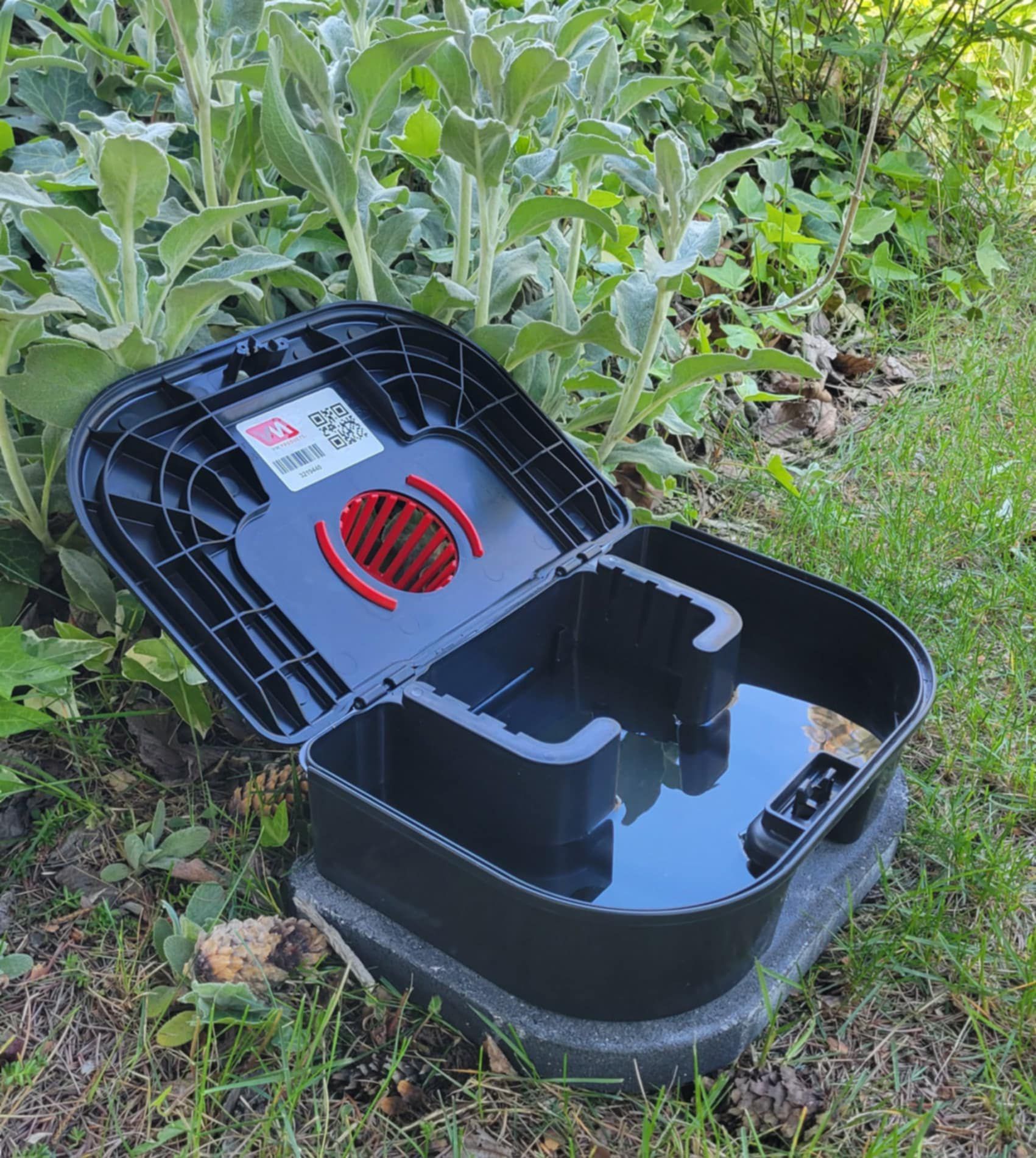 A black box with the lid open is sitting in the grass