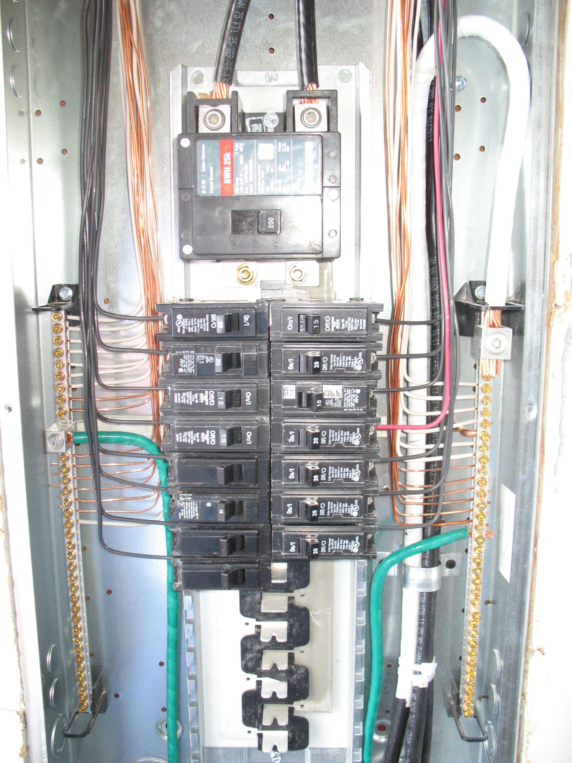 Electrical panel with circuit breakers and wiring inside a metal box.