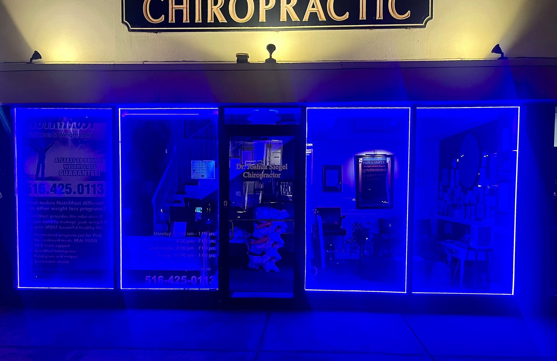 Chiropractic office front with blue neon lights around windows and door.