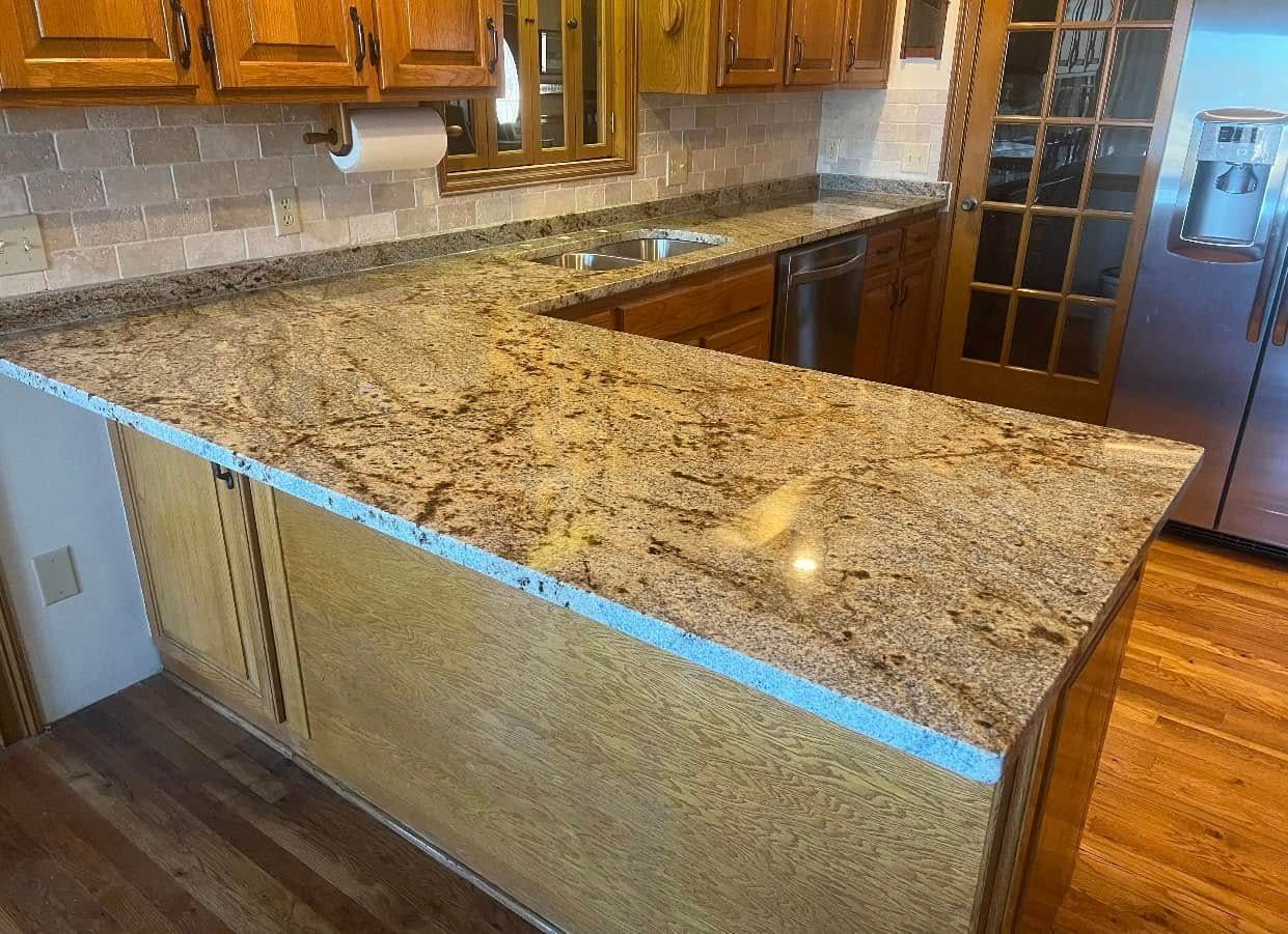 L-shaped kitchen countertop with granite in a home with wood cabinets and flooring.