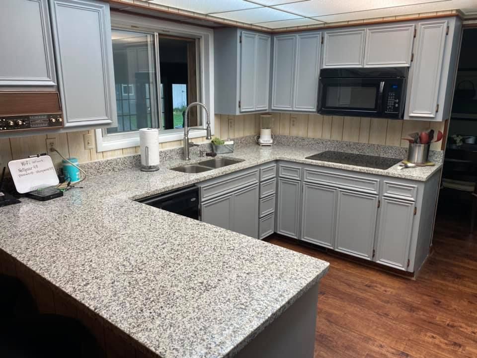 Gray kitchen with granite countertops, cabinets, and black appliances.