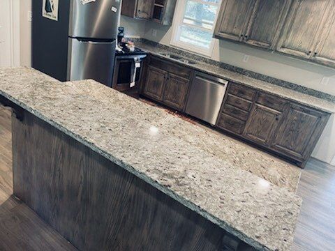 Kitchen with light granite countertops, stainless steel appliances, and dark wood cabinets.