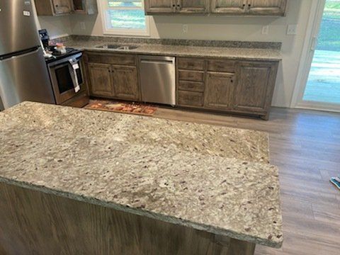 Kitchen with light granite countertops, wood cabinets, stainless steel appliances.