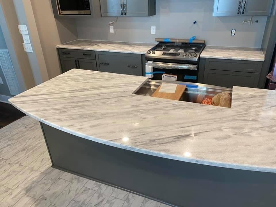 Kitchen with gray cabinets, white marble countertops, and stainless steel range.