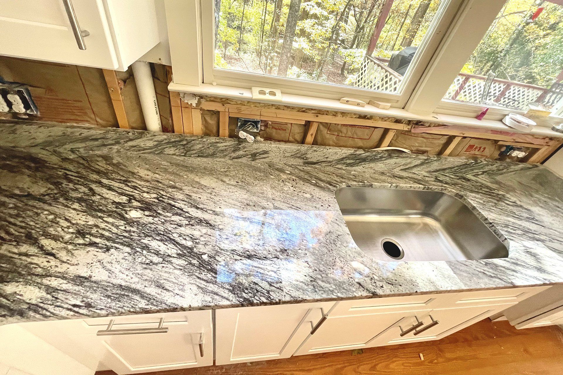 Kitchen countertop with granite, stainless steel sink, and white cabinets.