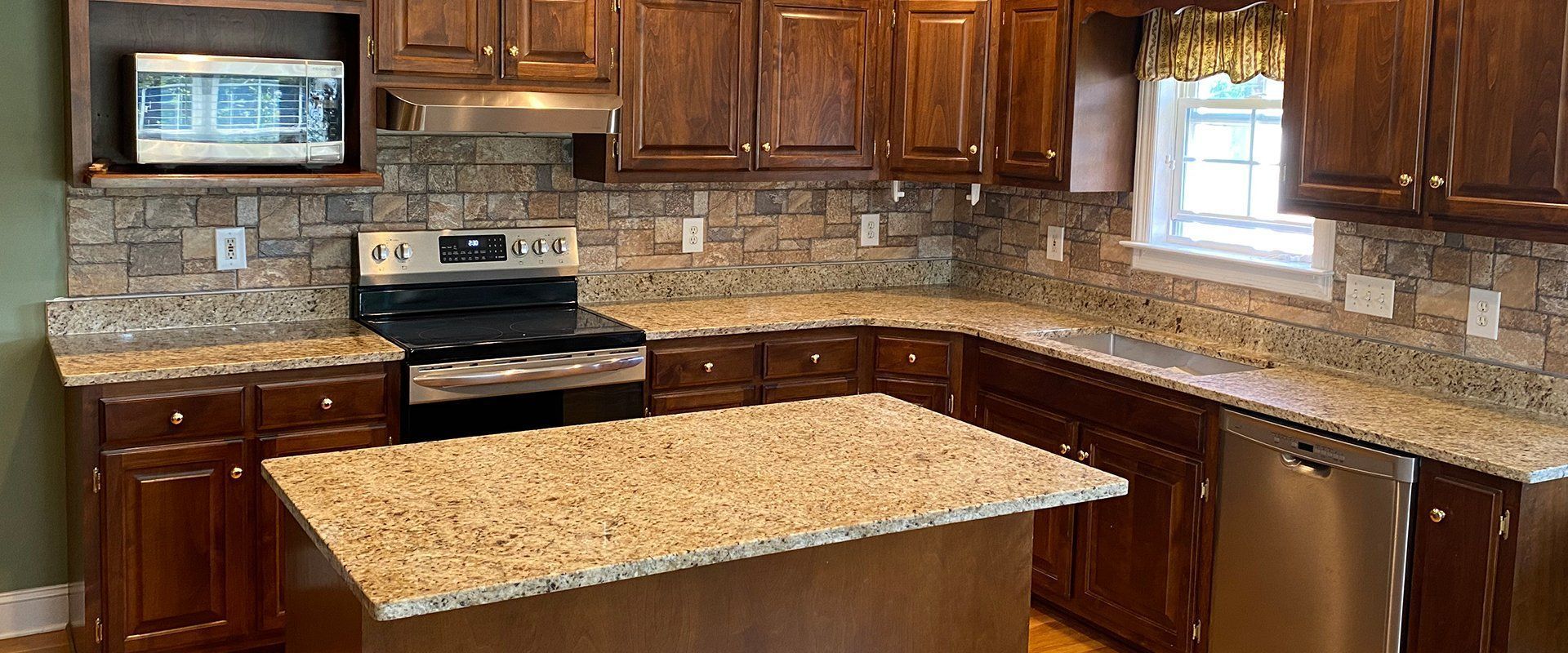 Kitchen with dark brown cabinets, granite countertops, and stainless steel appliances.