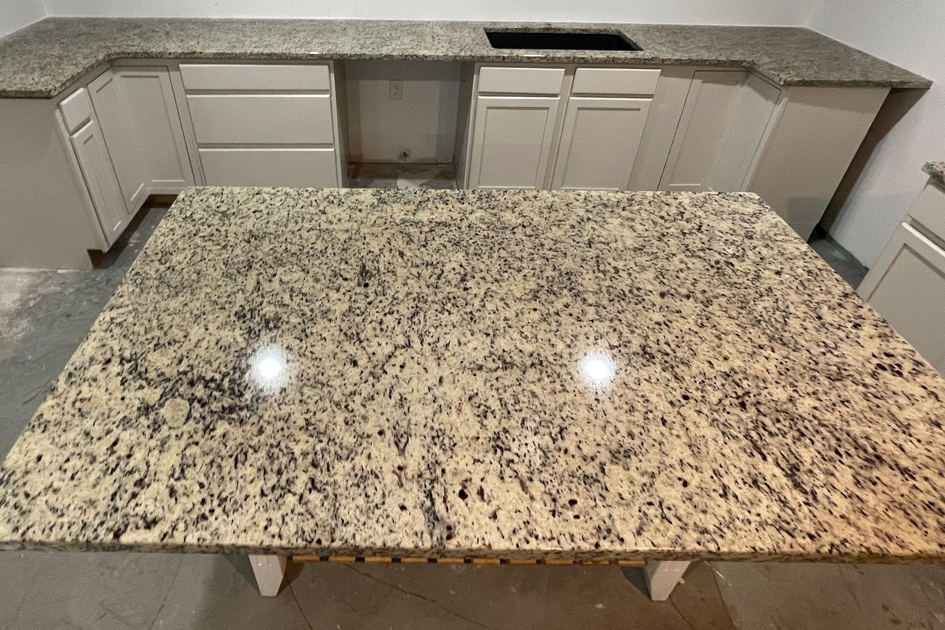 Kitchen with granite countertops and island. Beige cabinets and speckled granite.
