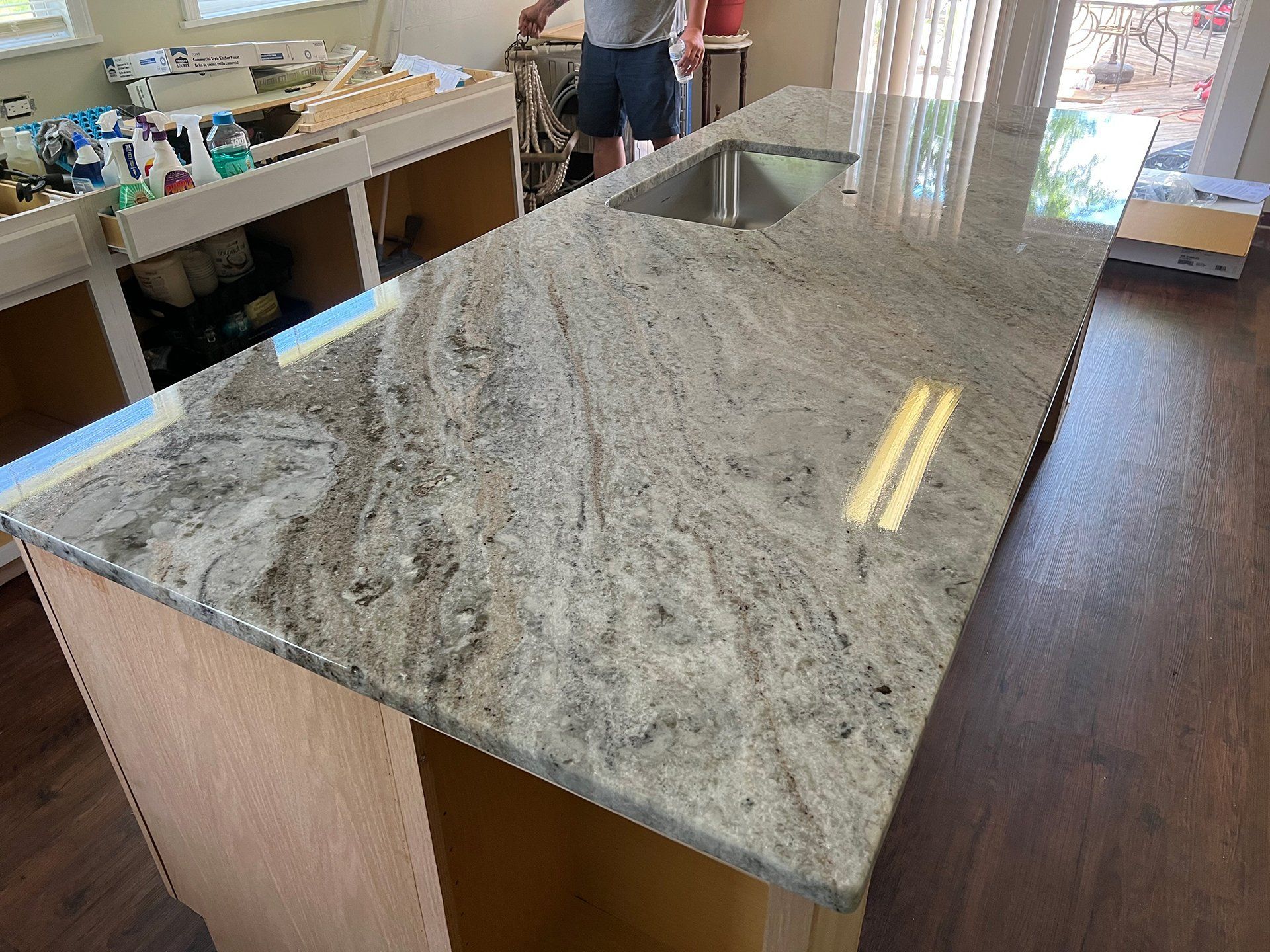 Granite countertop on a wooden island in a kitchen; person in background.