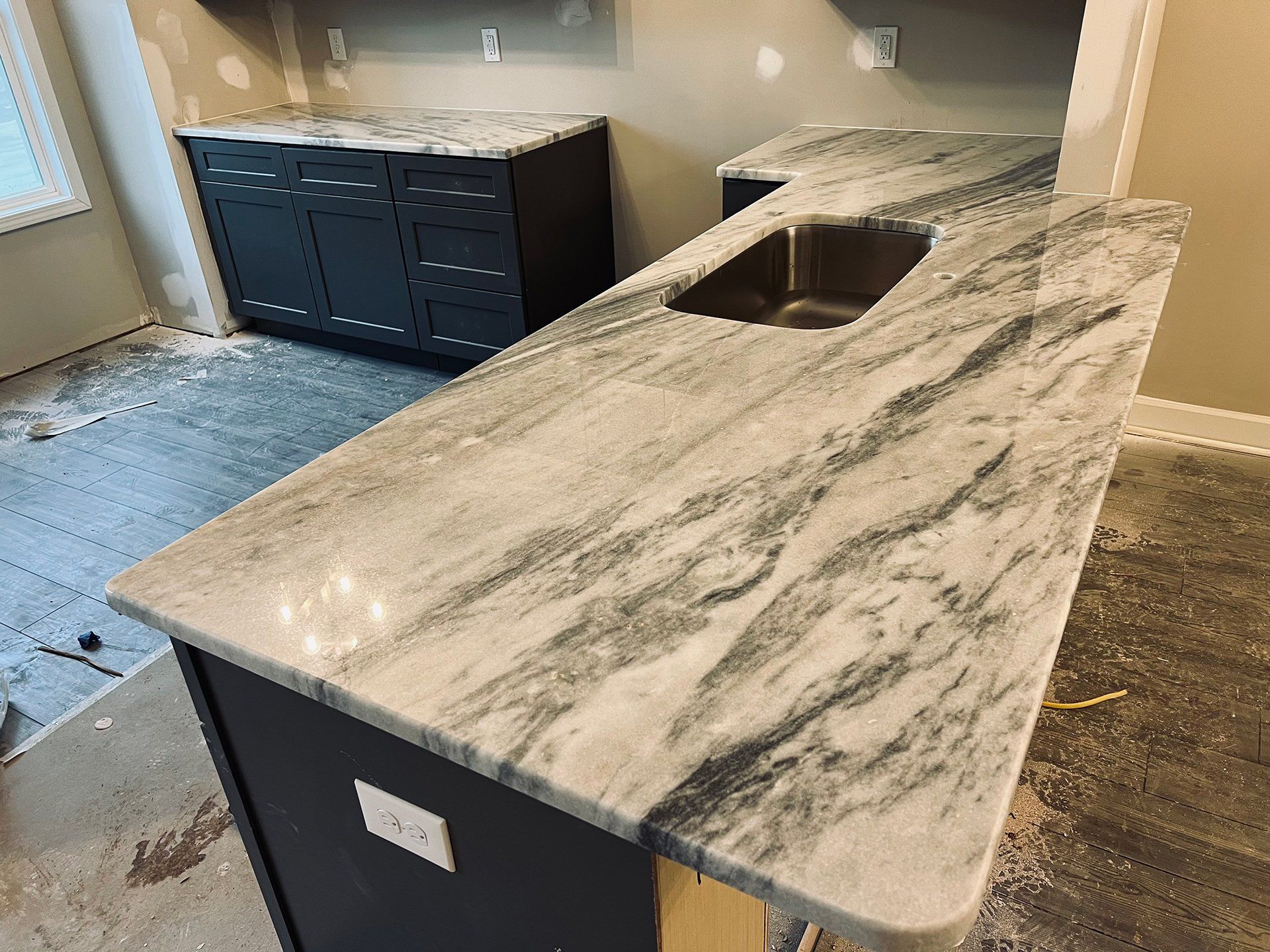 Kitchen with dark cabinets, light countertops, and a sink. Under construction.