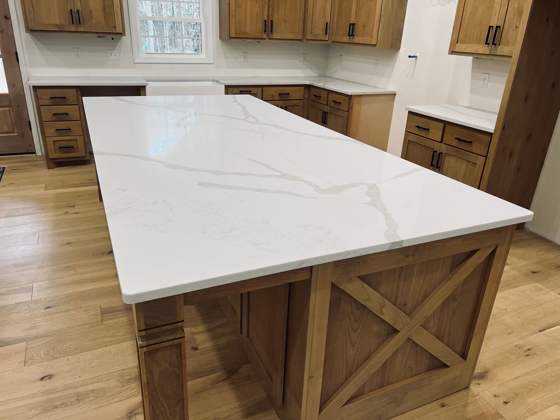 Wooden kitchen with white countertop island, cabinets, and hardwood floors.