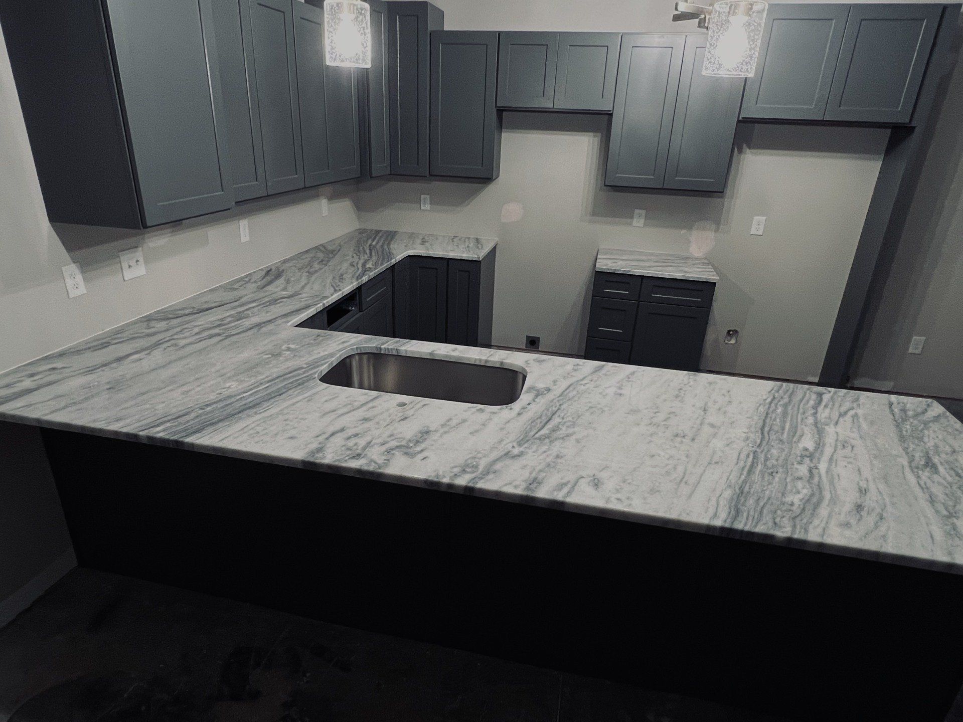 Modern kitchen with gray cabinets and a white and gray patterned countertop.