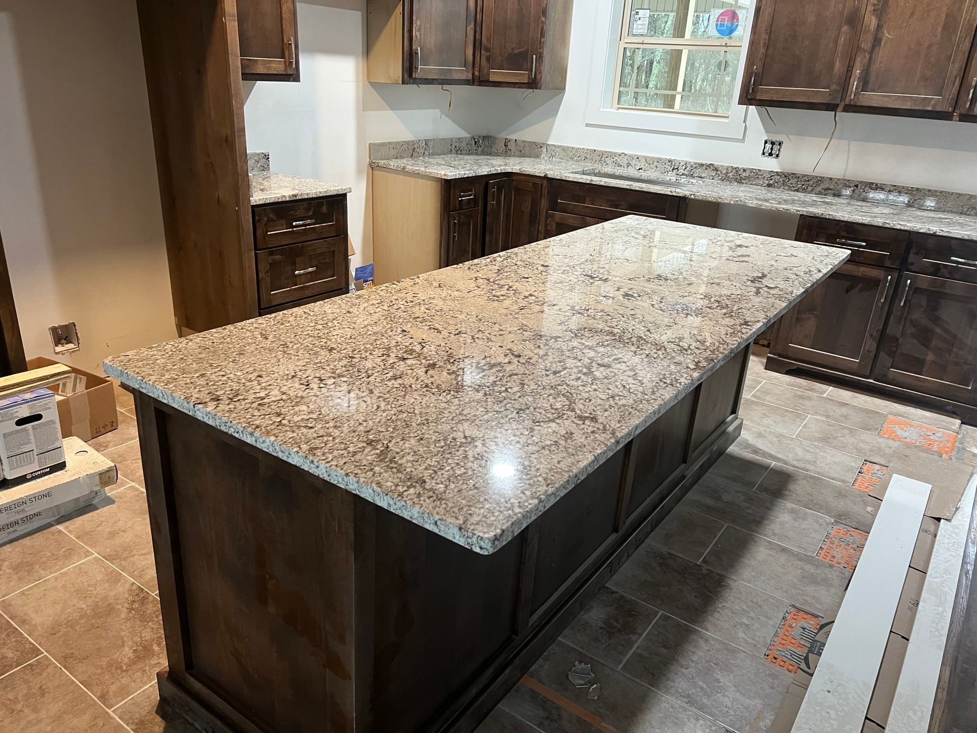 Kitchen with brown cabinets, granite countertops, and a large island in progress.