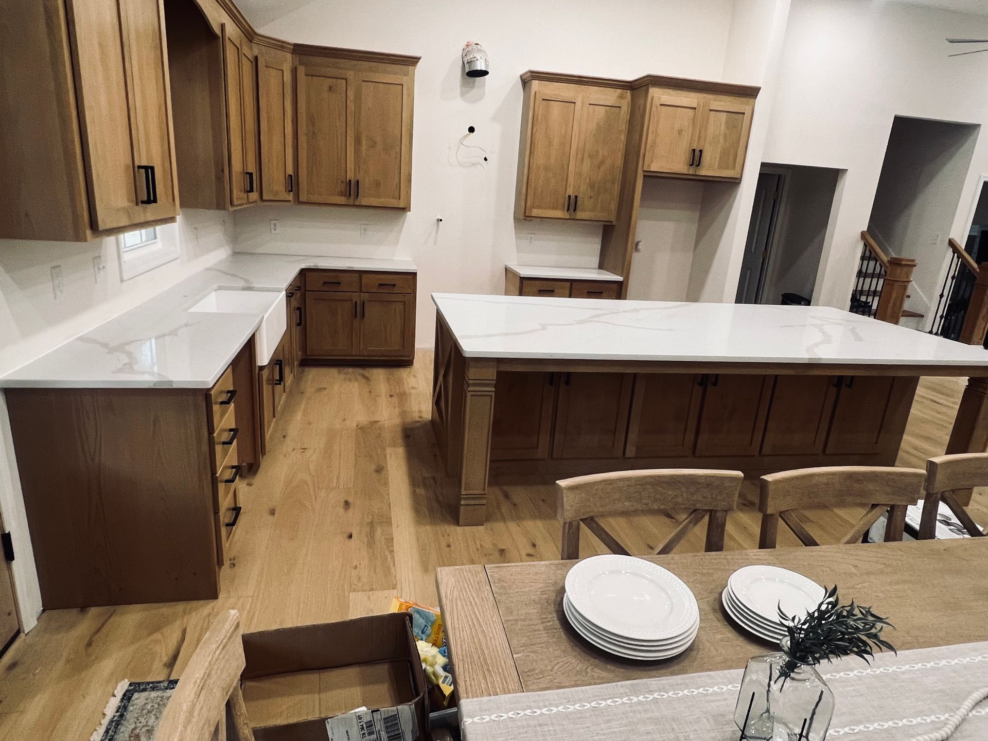 A kitchen with light wood cabinets, white countertops, and a large island.