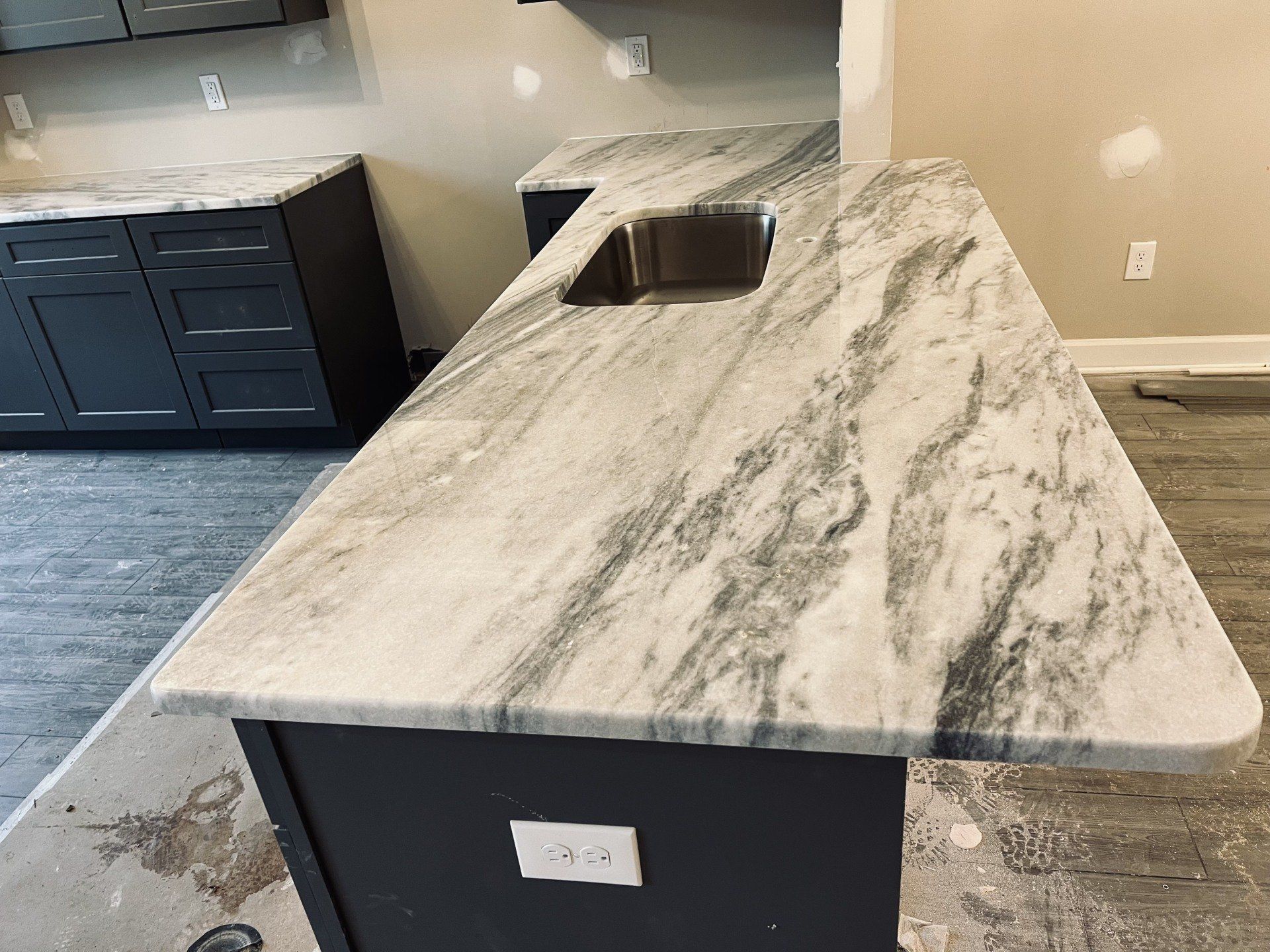 Kitchen with dark cabinets and a marble countertop island with a sink.