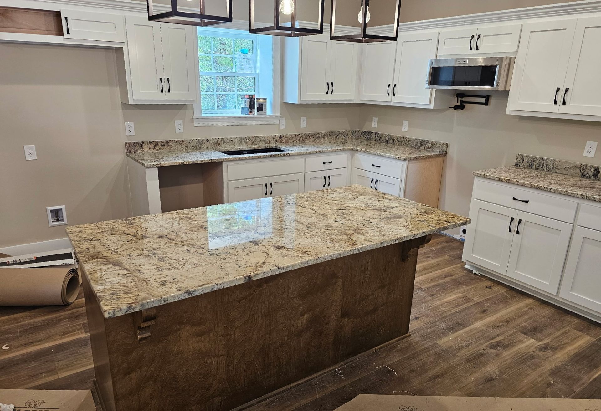 Kitchen with white cabinets, granite countertops, and a wood island.