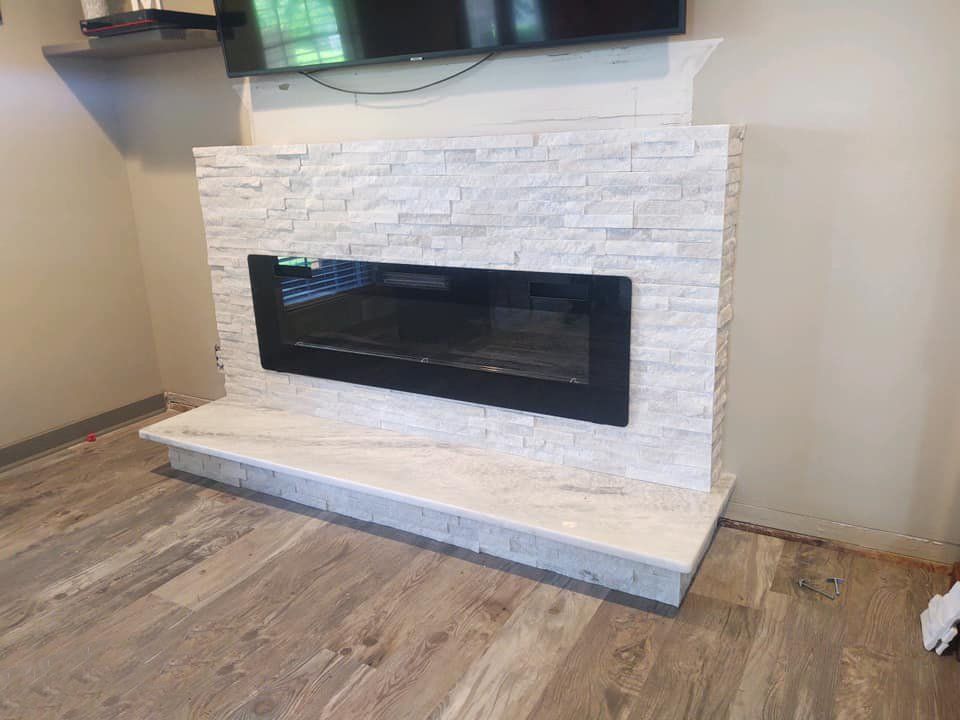 Electric fireplace with a black frame, white stone facade, and light wood-look floor.