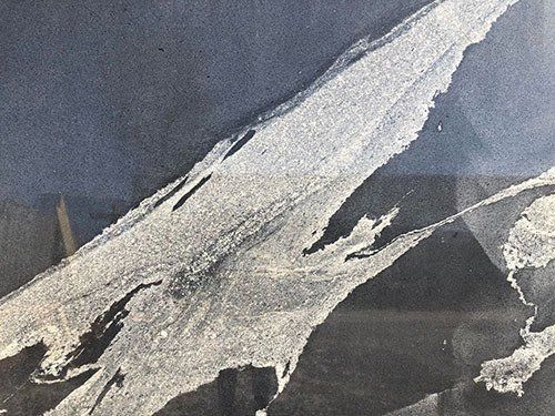 White, textured strokes on a dark blue and black surface; abstract, perhaps torn paper.