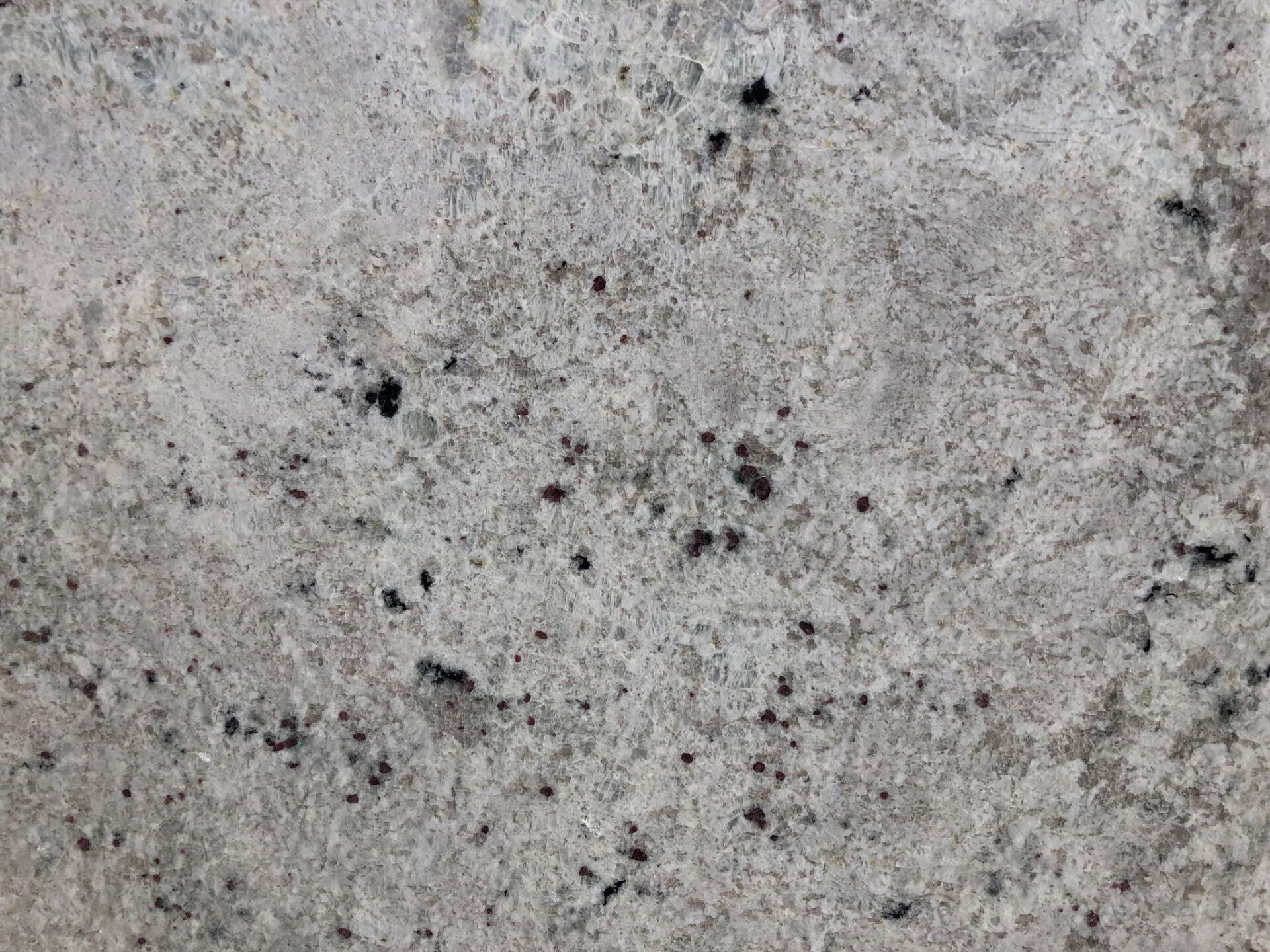 Gray mottled concrete surface with dark speckles.
