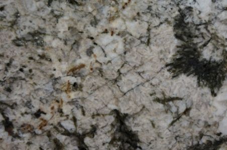 Close-up of granite countertop with light gray, white, and dark green mineral patterns.
