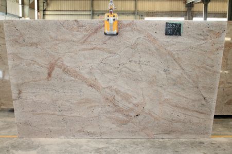 Large granite slab with beige and pink veining, being lifted in a warehouse setting.