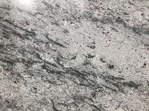 White granite countertop with gray veining and flecks of color.