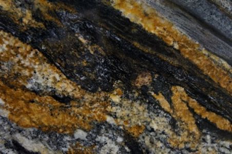 Close-up of a granite surface with flowing patterns of black, gold, and gray.