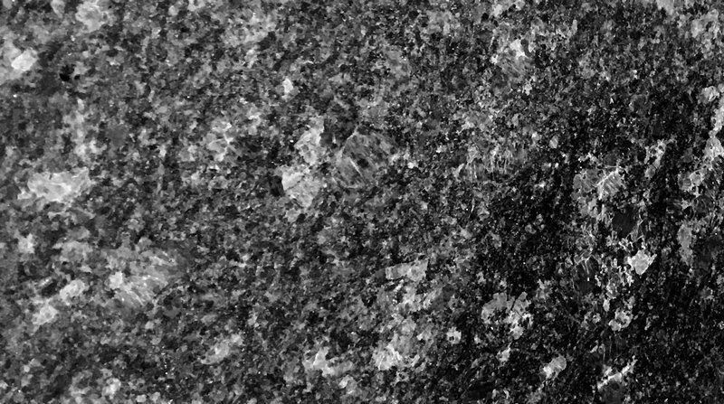 Close-up of dark, textured surface speckled with small, shiny, crystalline pieces.