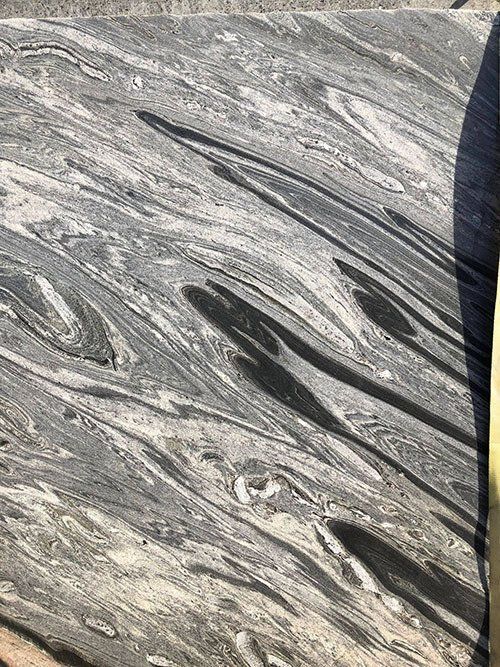 Swirling gray and white granite stone with dark streaks and organic patterns.