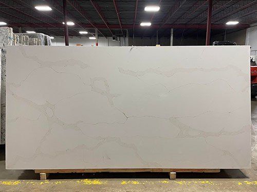 Large, light gray quartz slab with veining, resting on a wooden pallet in a warehouse.
