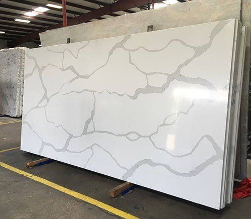 White quartz countertop slab with gray veining, propped up in a warehouse.