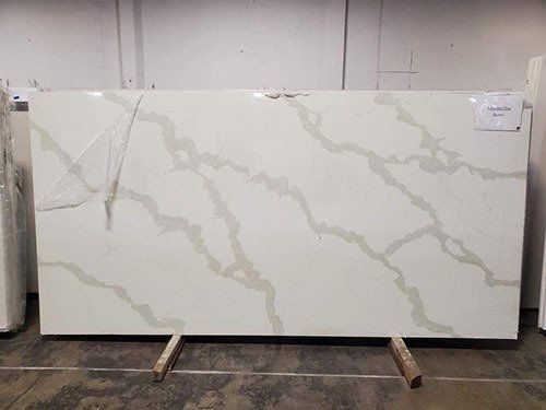 White quartz countertop with light gray veining, resting on a wooden support in a warehouse.