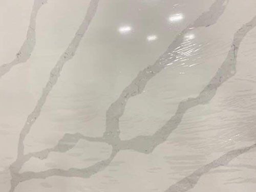 White quartz countertop with grey veining, shiny surface.