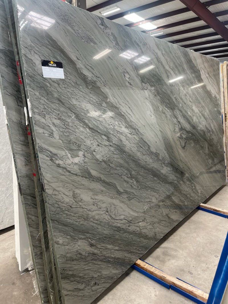 Large slab of gray and green granite, displayed in a warehouse.