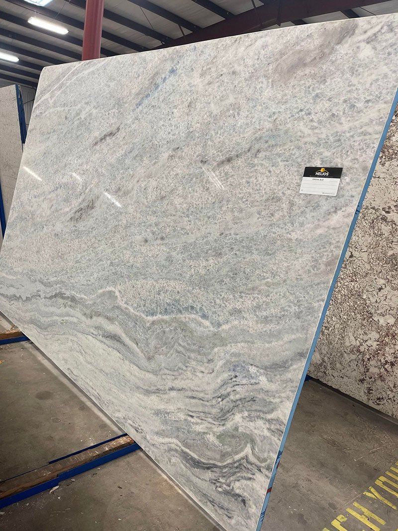 Large slab of blue, white, and grey granite in a warehouse setting, angled on a metal rack.