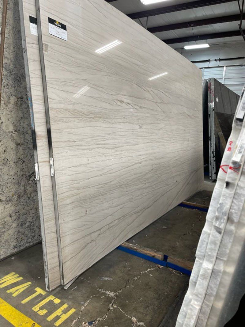 Large light-colored stone slab with veining in a warehouse setting.