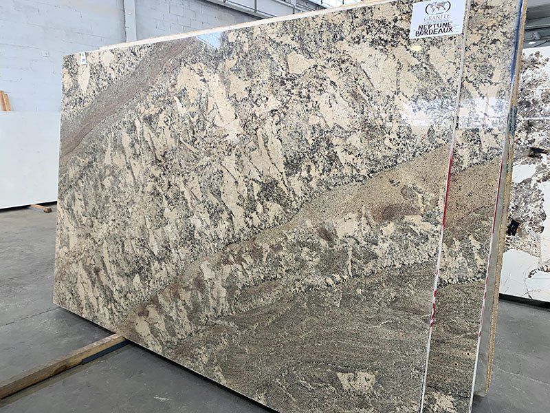 Large slabs of granite with beige, brown, and gray swirling patterns, indoors.