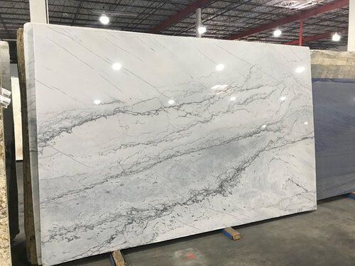 Large white marble slab with gray veining, propped up indoors.