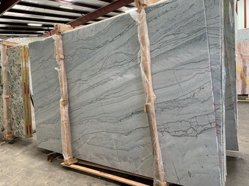 Large slabs of blue-gray stone with veining, stacked in a warehouse, ready for use.