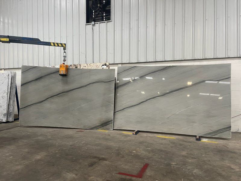Two large slabs of light gray marble with dark veining, inside a warehouse.