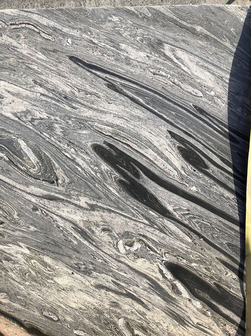 Gray and black swirled stone surface, with light and dark streaks resembling flowing water.