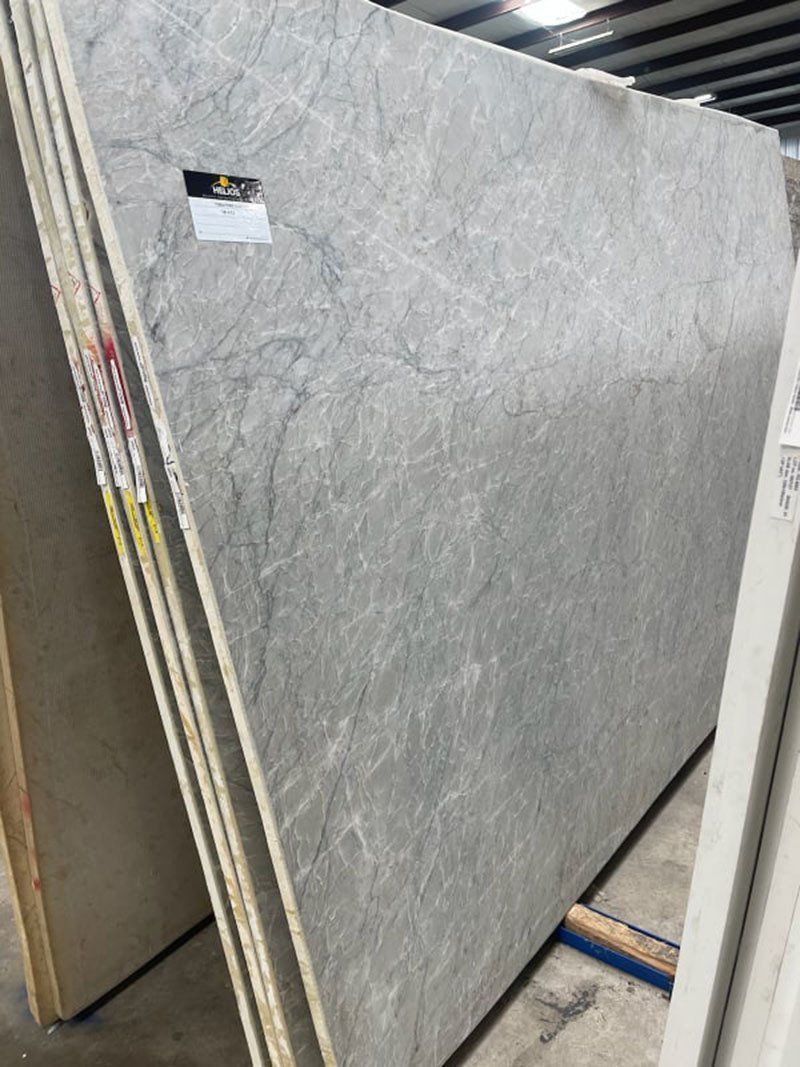 Gray marble slab leaning against other slabs in a warehouse.