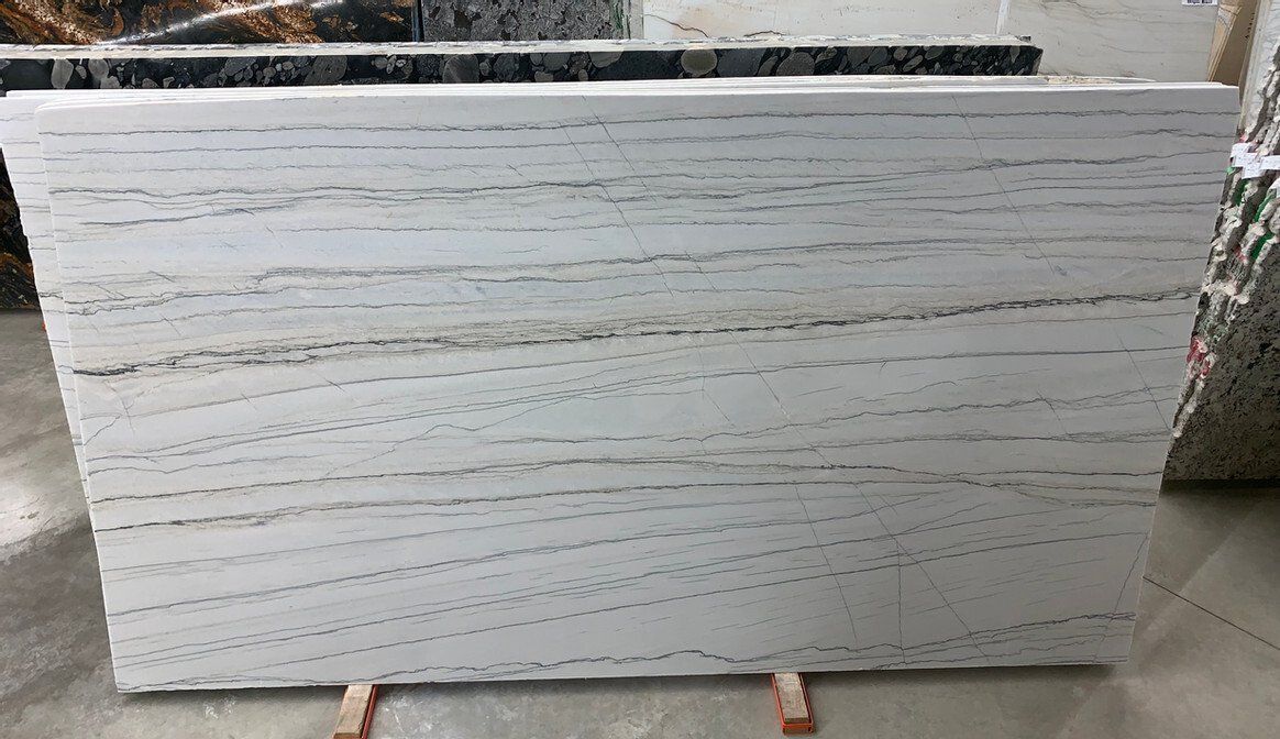 White marble slab with horizontal gray veining, displayed in a showroom.