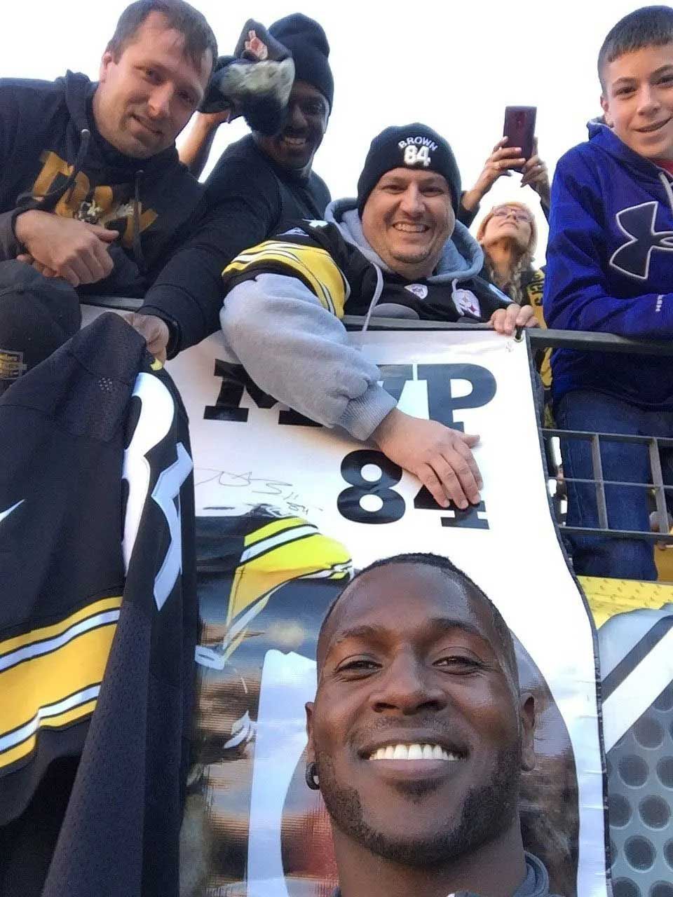 Football player taking a selfie with fans, holding a banner with